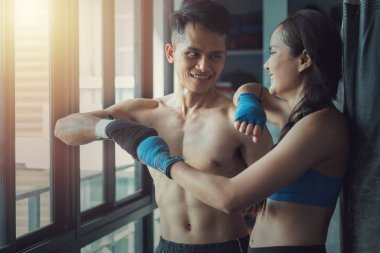 Two young fit professional Southeast Asian boxers smiling and bumping fists