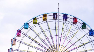The colorful Ferris wheel in the background of the cloudy sky