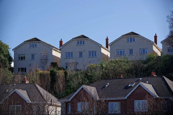 Row of identical detached houses built on the hill overlooking a residential area.