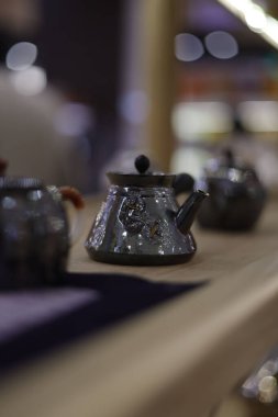 A vertical shot of the tiny ceramic teapot on a wooden shelf in the kitchen