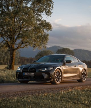 Günbatımında modern bir BMW M4 'ün, Dağ v. lüks spor arabalı görüntüsü birçok sürücünün hayalindeki arabadır.