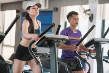 Two young Asian people training on a treadmill.