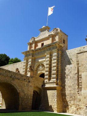 A vertical shot of an ancient castle and a waving flag on its top in Mdina, Malta