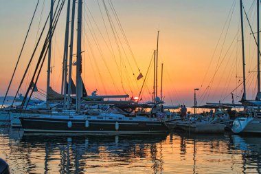 A bright orange blue sunset sky over a pier with boats in Naxos, Greece