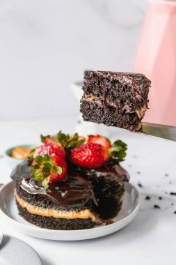 Çilekle süslenmiş çikolatalı pastanın dikey görüntüsü.