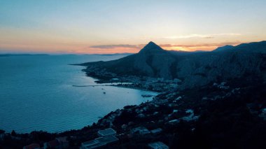 Gün batımında deniz kenarındaki dağların panoramik görüntüsü