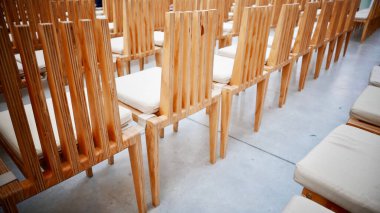 Beyaz döşeme üzerinde beyaz şilteli ahşap sandalyeler.