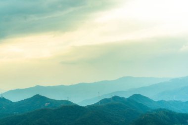 Şafak vakti bulutlu gökyüzünün altındaki yeşil dağların kuş bakışı görüntüsü.