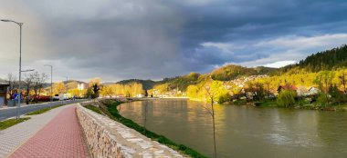 Şehirdeki bir nehrin üzerinde kasvetli bulutlu bir manzara.