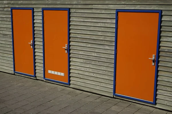 Orange doors with blue frames in wooden house wall (horizontal), Zandvoort, North Holland, Netherlands