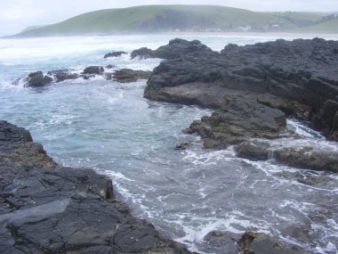 Büyük köpük dalgaları kayalık bir sahile çarpıyor.