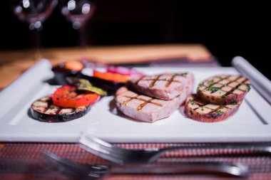 Bir tabak ızgara tavuk göğsü. Izgara patates, domates ve soğan.