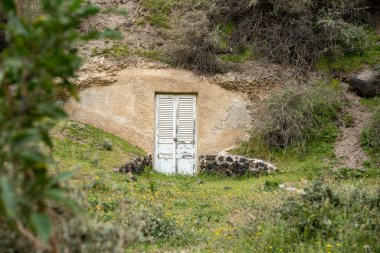 Tepedeki beyaz ahşap kapının seçici odak noktası.