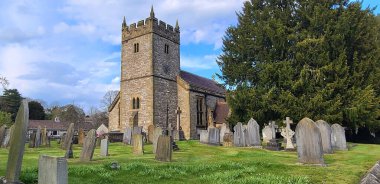 Mavi bulutlu gökyüzünün altında mezarlığı olan güzel bir kilise manzarası.