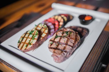 Kızarmış patates, domates ve soğanlı bir tabak et.