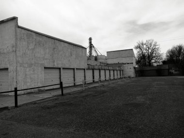 Bulutlu bir günde garaj kapısı olan bir binanın gri tonlu görüntüsü.