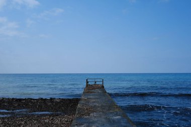 Bulutlu gökyüzünün altında mavi okyanusun üzerindeki eski bir iskelenin güzel manzarası.
