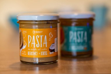 Krukam marka bir hindistan cevizi fıstığı pastası. Masada cam bir kavanozda beyaz çikolata var.