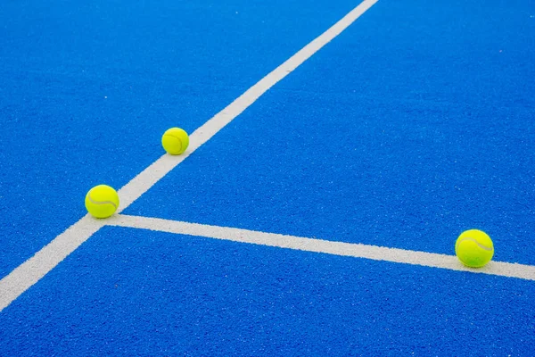 racket sports, three balls on the lines of a blue paddle tennis court