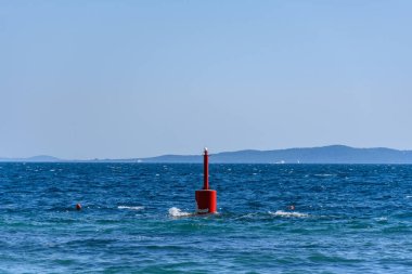 Mavi denizde yüzen kırmızı bir şamandıra.