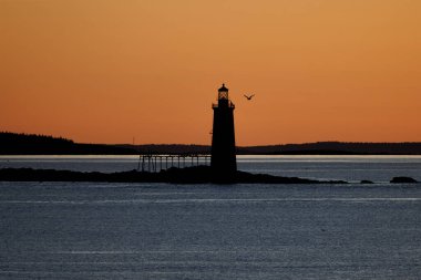 Gün batımında bir deniz fenerinin silueti