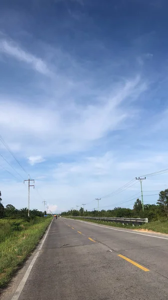 長い高速道路の上に白い雲と青い空の垂直ショット — ストック写真