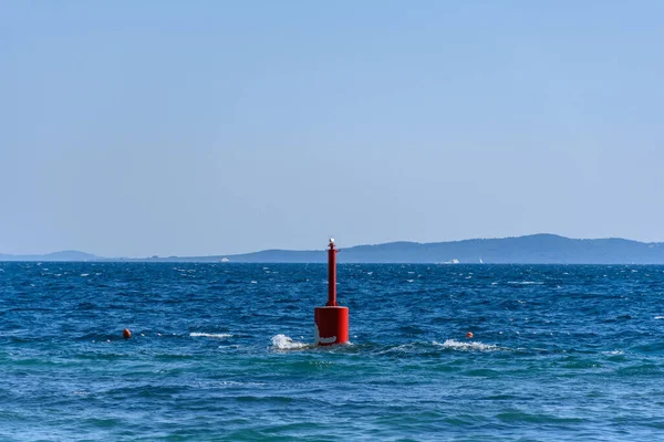 Mavi denizde yüzen kırmızı bir şamandıra.