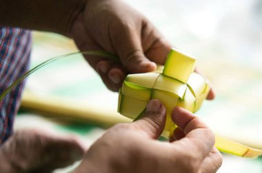 Hindistan cevizi yapraklarını örerek Ketupat - pirinç keki - hazırlayan birinin ellerine yakın çekim