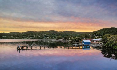 Denizin üzerinde iskelesi olan yeşil dağların inşa ettiği bir tatil köyünün büyüleyici manzarası.