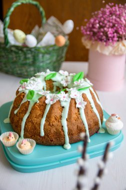 Üzerinde beyaz çiçekler ve yeşil yapraklar olan Paskalya bademli pasta.