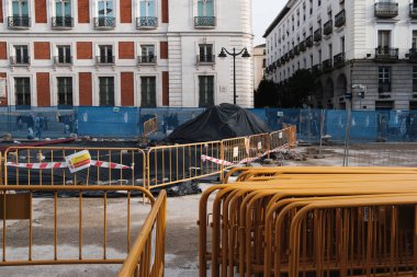 A number of yellow, metal moving gates outdoors in a Madrid's most known square which is puerta del sol in daylight