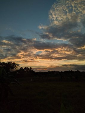 A view of a beautiful sunset over the green field
