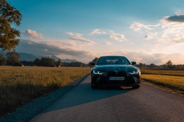 Günbatımında modern bir BMW M4 'ün, Dağ v. lüks spor arabalı görüntüsü birçok sürücünün hayalindeki arabadır.