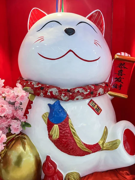A vertical closeup shot of an oriental Asian white cat sculpture