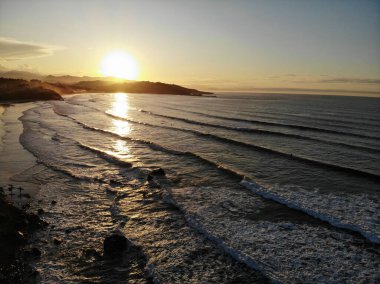 A beautiful view of the sunset with ocean waves rolling into the shore