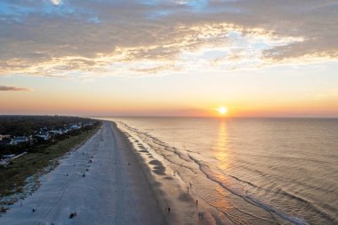 Hilton Head Adası 'ndaki Coligny plajının kuş bakışı görüntüsü. Gün batımında okyanus manzaralı ve ön planda ağaçlar ve oteller var.