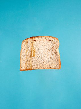 Mavi arka planda izole edilmiş bir dilim ekmeğin dikey çekimi