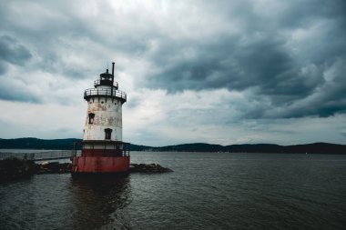 A view of Tarrytown lighthouse surrounded by water under cloudy sky