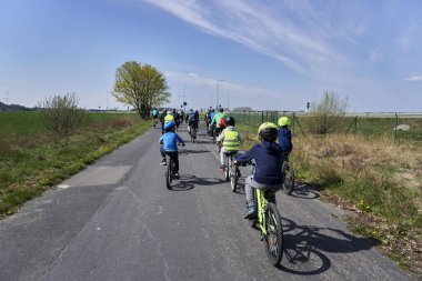 A Group of people riding bicycles on an asphalt footpath during a bike trip
