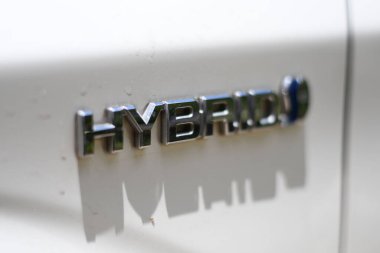 A closeup of a hybrid text mounted on car body