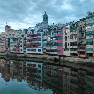 The colored houses of Girona and their reflection in the river from one of the bridges