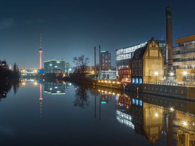 Berlin 'de Spree nehrinin arka planında televizyon kulesi olan eski binalar var.