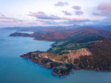 Yeni Zelanda 'da mavi gökyüzünün altında suyla çevrili bir dağ manzarası.
