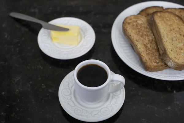 在黑桌上放有切好的面包和黄油的一杯咖啡的特写 — 图库照片