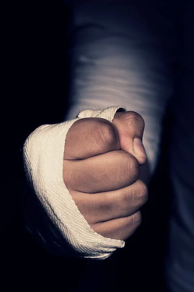 A selective focus shot of a male\'s fist with white bandage  on a black background
