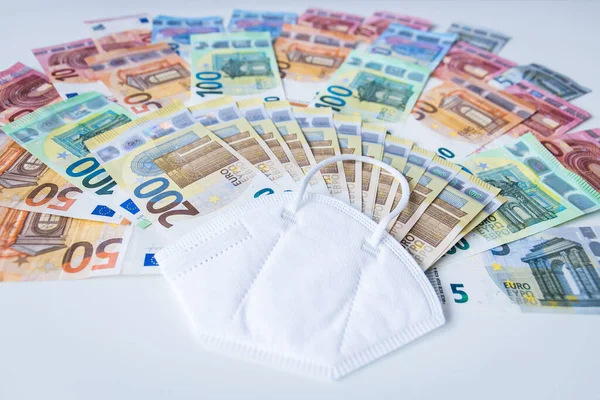 白い机の上にユーロ紙幣の束とコロナフェイスマスク — ストック写真