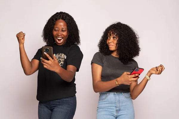 Beautiful Shot Two African Girls Checking Phones One Happy Other — Stock fotografie