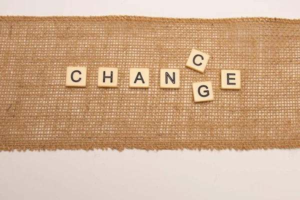 Change into Chance concept in letter tiles laid on Hessian jute cloth isolated on white background.