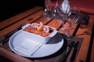 Masadaki parlak tencerede deniz ürünleri lazanyası.