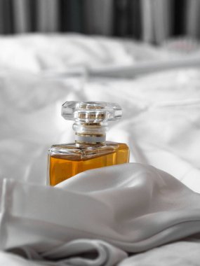 Bulanık bir arkaplanda beyaz bir bez arasında lüks bir kadın parfüm şişesinin dikey çekimi..
